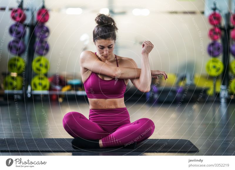 Junge Frau macht Dehnungsübungen auf einer Yogamatte im Fitnessstudio Lifestyle Körperpflege Wellness Club Disco Sport Mensch feminin Erwachsene Jugendliche