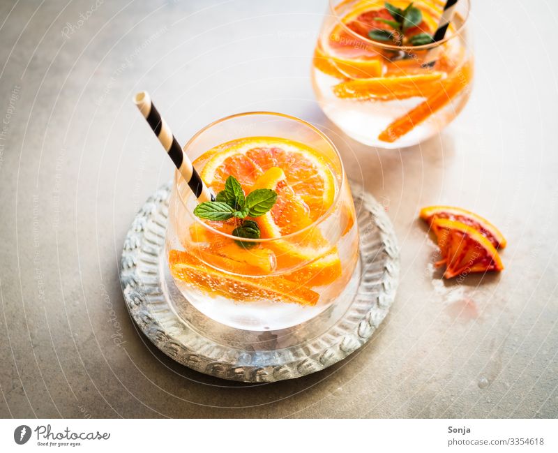 Cocktail mit frischen Orangen und Pfefferminze in einem Glas Kräuter & Gewürze Minze Diät Getränk Trinkwasser Limonade Saft Longdrink Teller Trinkhalm Lifestyle