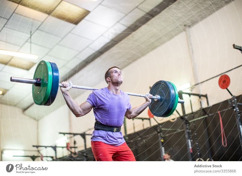 Muskulöser Mann hebt Langhantel im modernen Fitnessstudio Sportler Training Gewichtheben Curl-Hantel schwer anstrengen Erwachsener stark männlich angespannt
