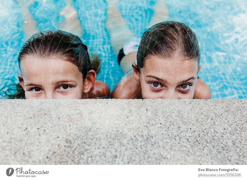 zwei wunderschöne Teenager-Mädchen, die in einem Pool schweben und in die Kamera schauen. Spaß und sommerlicher Lebensstil Aktion Schwimmbad Außenaufnahme