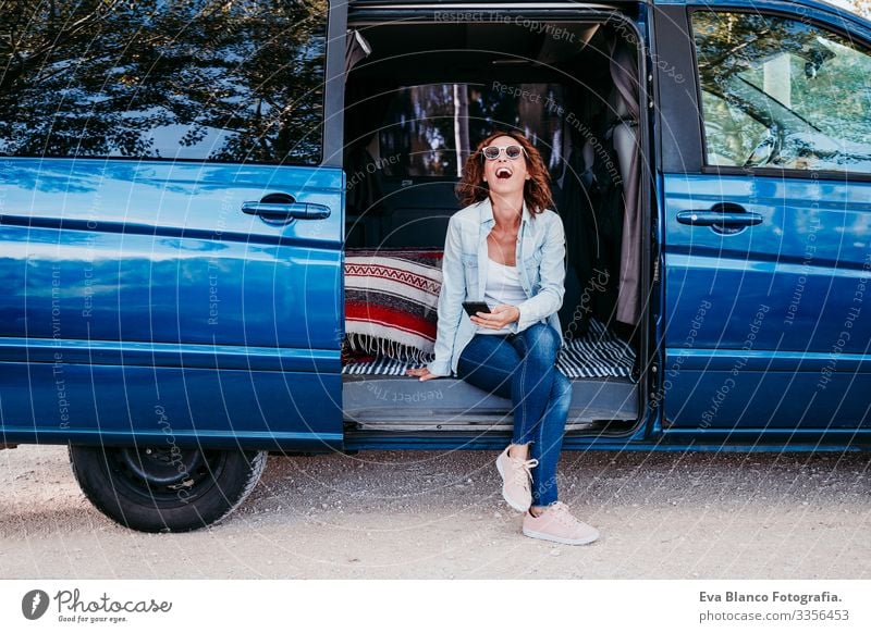 glückliche Frau, die in einem blauen Van sitzt und Spaß hat. reisekonzept Glück lachen Kleintransporter PKW Ferien & Urlaub & Reisen Handy genießend Freude