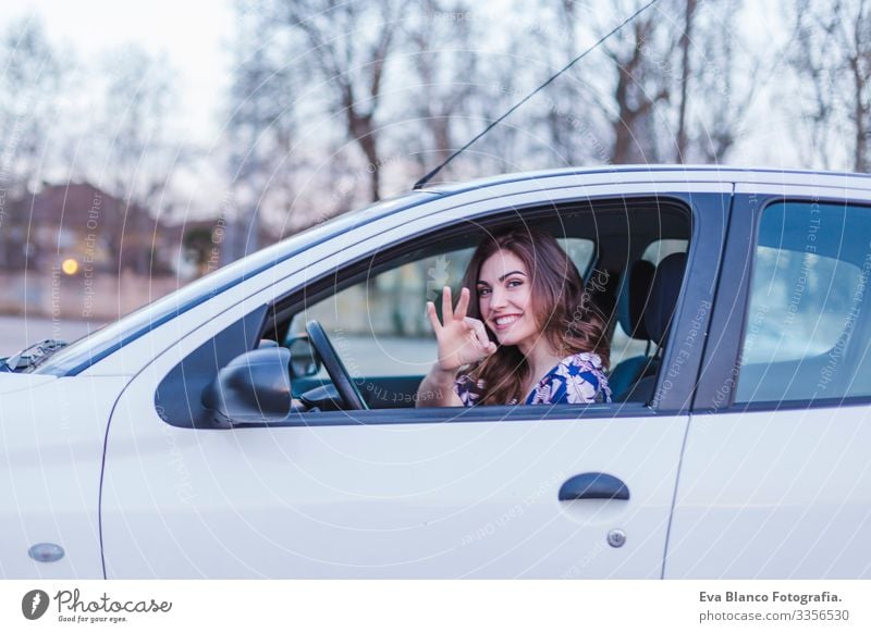 Junge Frau, die in der Stadt Auto fährt. Porträt einer schönen Frau in einem Auto, die aus dem Fenster schaut und lächelt. Reise- und Urlaubskonzepte