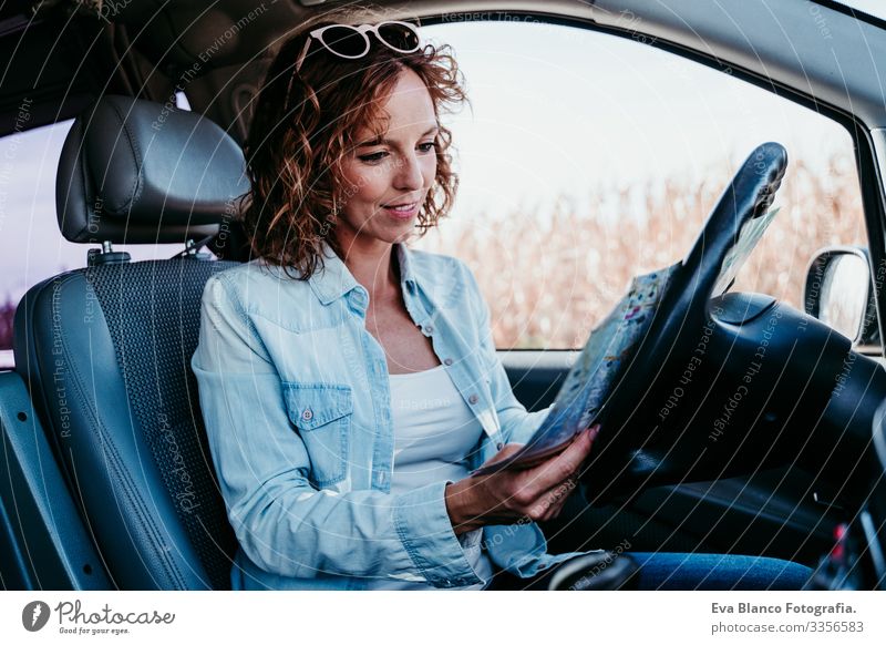 junge schöne frau, die im auto eine karte liest. reisekonzept Landkarte lesen Frau Jugendliche fahren PKW Sonnenstrahlen Sonnenbrille Ferien & Urlaub & Reisen