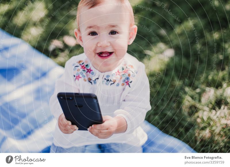 glückliches Baby, das sein Handy im Freien benutzt. technologiekonzept Mutter Technik & Technologie Zusammensein Kind Kindererziehung Mädchen Freude