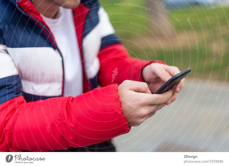 Junger Mann mit einem Smartphone in der Hand schreibt draußen auf der Straße SMS Mobile Beteiligung benutzend Telefon Technik & Technologie Handy Gerät