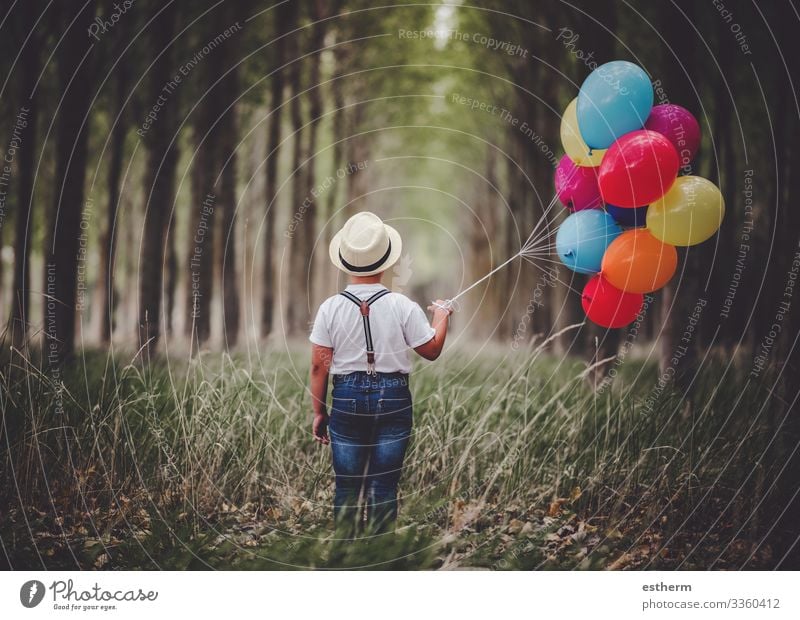 Rückansicht eines nachdenklichen Kindes mit Luftballons im Wald im Freien Lifestyle Erholung Ferien & Urlaub & Reisen Freiheit Sommer Mensch maskulin Junge