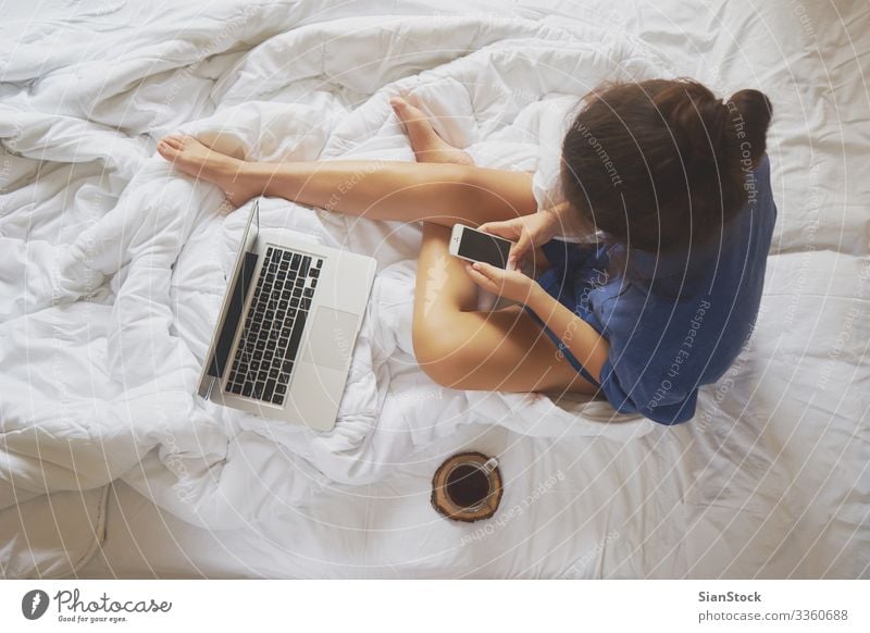Junge Frau zu Hause in ihrem Bett und überprüft ihr Smartphone Kaffee schön Leben Erholung lesen Schlafzimmer Arbeit & Erwerbstätigkeit Arbeitsplatz Computer