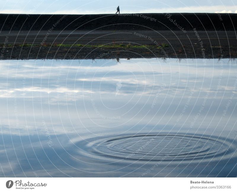 Spaziergänger am Wasser hinter gespiegeltem Himmel mit Wasserkreis Spaziergang Kai Ufer Wasserspiegelung Wasserkreise Natur blau See Reflexion & Spiegelung
