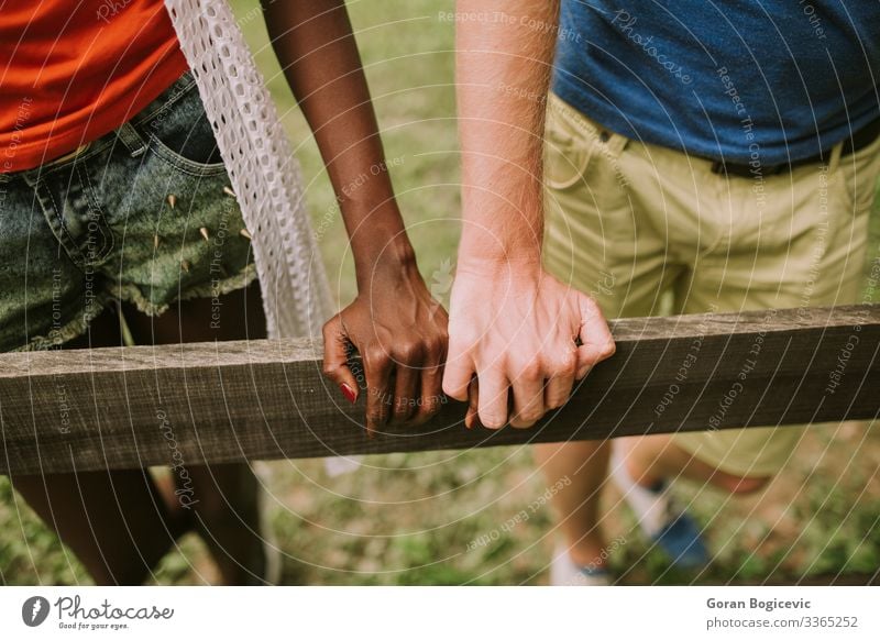 Mehrrassiges Paar im Park Lifestyle Sommer Mensch Frau Erwachsene Mann Arme Hand Holz Zusammensein modern schwarz Freund lässig Kaukasier Vielfalt Zaun aus Holz
