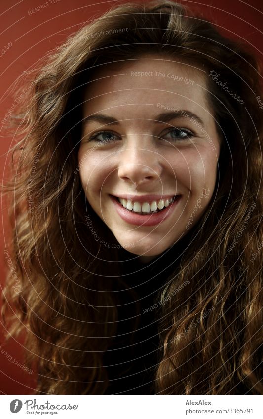 Portrait einer lächelnden, jungen Frau mit Grübchen vor einer roten Wand Lifestyle Stil Freude schön Leben Junge Frau Jugendliche Haare & Frisuren Gesicht