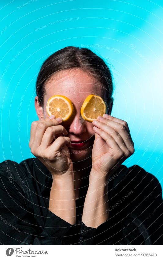 Junge Frau mit Zitronenscheiben über den Augen auf blauem Hintergrund Scheibe deckend Mädchen Überfall Konzept Minimalismus Zitrusfrüchte Frucht frisch Frische