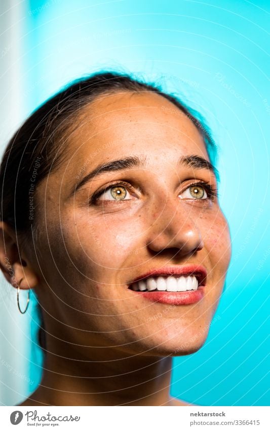 Lächelndes Gesicht einer jungen indischen Frau auf blauem Hintergrund haselnussbraune Augen Mädchen Zahnfarbenes Lächeln junger Erwachsener weibliche Schönheit