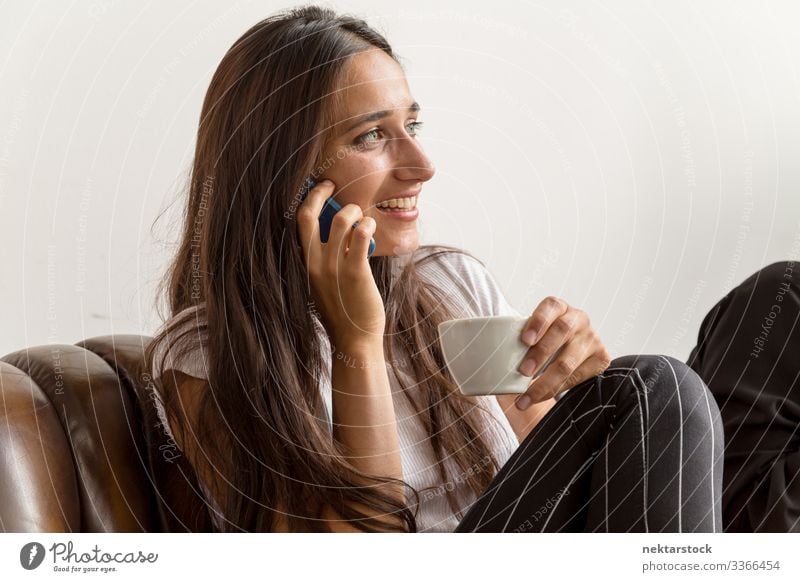Junge Frau spricht am Telefon und hält Kaffeetasse Telefongespräch Lächeln am Telefon sprechen Mädchen junger Erwachsener Tag natürliche Schönheit reales Leben