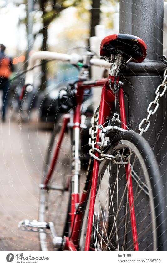 sicher am Pfahl Lifestyle Stil Fahrrad Stadt Verkehrsmittel Fahrradfahren Kette Schloss Holzpfahl Rennrad Fahrradsattel authentisch trendy retro rot schwarz