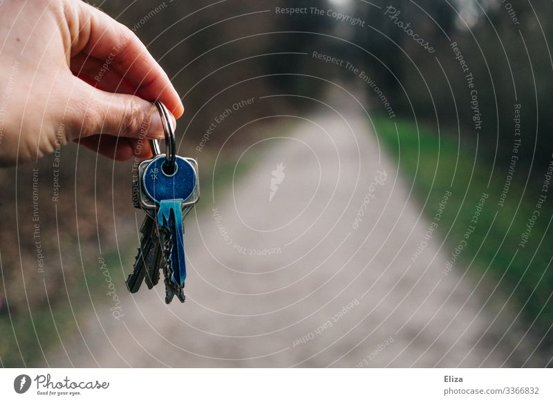 Eine Hand, die einen Schlüsselbund mit einem blauen Schlüssel hält oder übergibt, Wohnungsübergabe, Umzug, Eigenheim Textfreiraum Mitte Textfreiraum unten