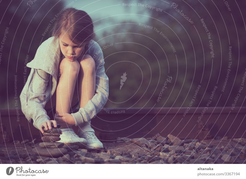 Porträt eines jungen, traurigen Mädchens, das tagsüber im Freien auf der Bahn sitzt. Konzept der Trauer. Gesicht Kind Mensch Frau Erwachsene