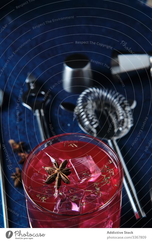 Köstlicher roter Cocktail und Barmann-Werkzeuge auf dem Tisch Eiswürfel Kulisse Barkeeper Gerät trinken Glas Getränk Alkohol kalt liquide kreativ ausgefallen