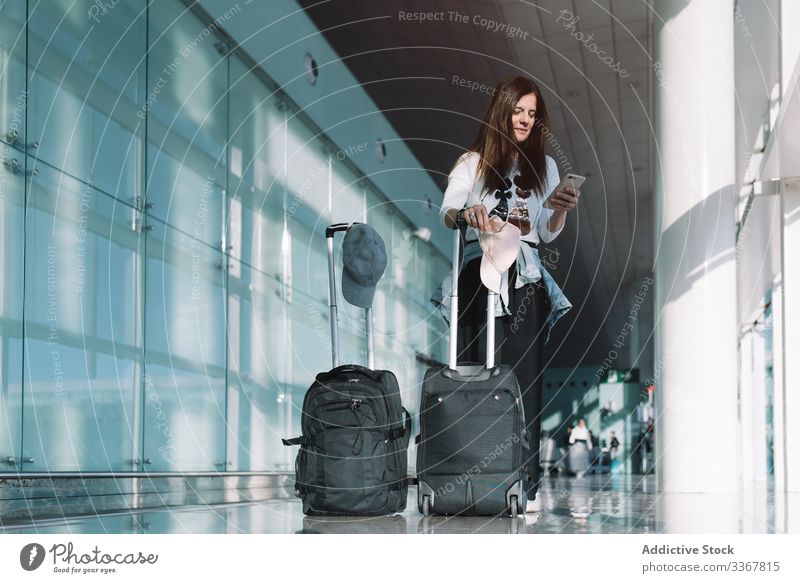 Ruhige Frau telefoniert am Flughafen Telefon Surfen benutzend Gepäck Urlaub Abheben Ankunft Abenteuer Tasche warten Smartphone Verzögerung Öffentlich