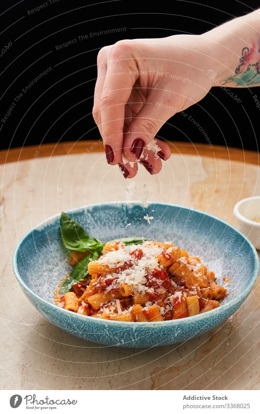 Anonymer Chefkoch serviert Pasta in Schüssel Küchenchef Servieren Essen zubereiten Spätzle Nudeln funkelnd Käse gerieben Tomatensauce Schalen & Schüsseln Teller