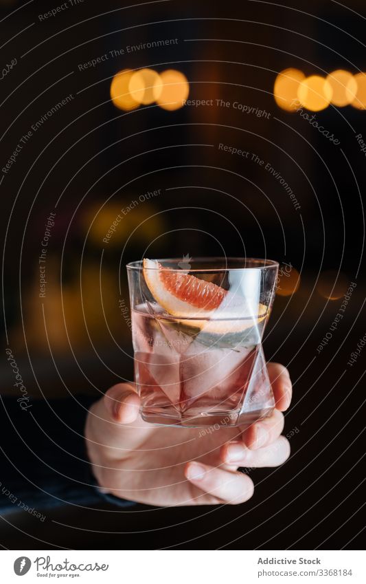 Anonyme Person mit alkoholischem Getränk mit geschnittener Grapefruit und Eis Cocktail Zitrusfrüchte Alkohol Bar Tisch trinken Tasse Glas Erfrischung kalt