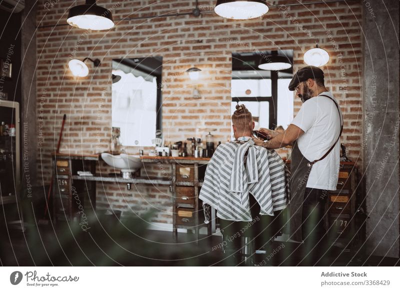 Friseur schneidet einem anonymen rothaarigen Mann die Haare Klient trendy Barbershop bärtig Maskulinität Kunde Behaarung Pflege Salon Hipster gutaussehend