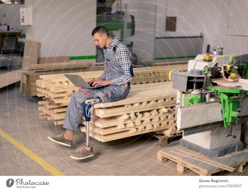 Behinderter junger Mann, der in einer Möbelfabrik arbeitet Arbeit & Erwerbstätigkeit Beruf Handwerker Arbeitsplatz Fabrik Industrie Business Notebook Werkzeug