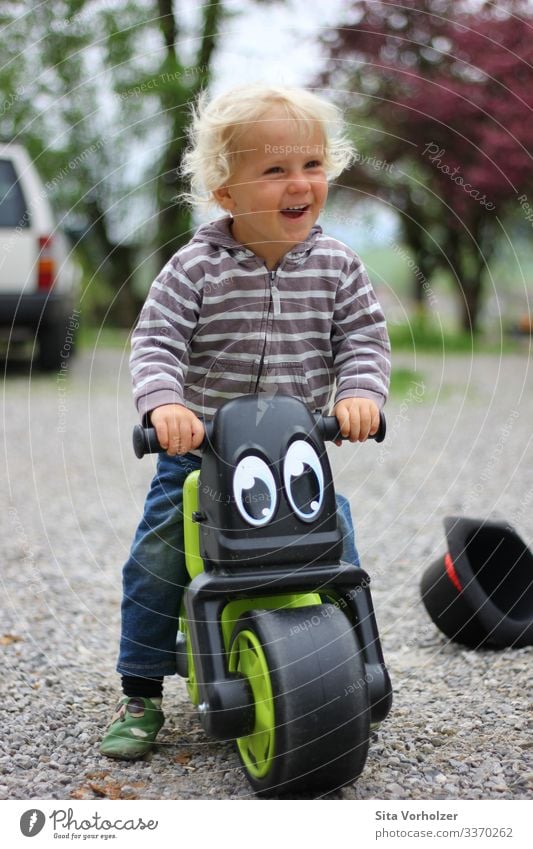 Lachender Junge auf Laufrad Freizeit & Hobby Sommer Fahrradfahren Kindererziehung Mensch maskulin Kleinkind Kindheit 1 1-3 Jahre Frühling Park Hut blond Locken