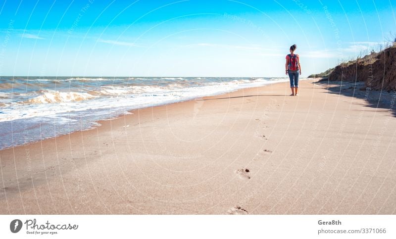 eine Touristin mit rotem Rucksack an einem leeren Sandstrand Ferien & Urlaub & Reisen Freiheit Sommer Strand Meer Wellen Frau Erwachsene Natur Landschaft Himmel