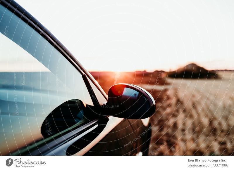 Nahaufnahme eines Autos und eines Rückspiegels bei Sonnenuntergang auf einem Feld. Reisekonzept PKW reisen sonnig Landschaft gelb niemand Ansicht sportlich