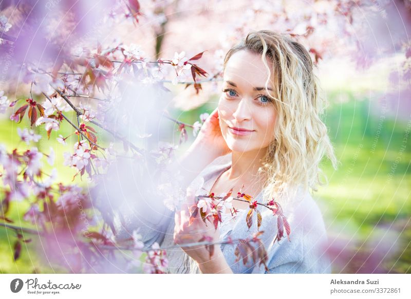 Junge Frau genießt die Natur im Frühling. Atmen frische Luft und Blumen Aroma in schönen Park mit Kirschbäumen in der Blüte. Glück Konzept Beautyfotografie
