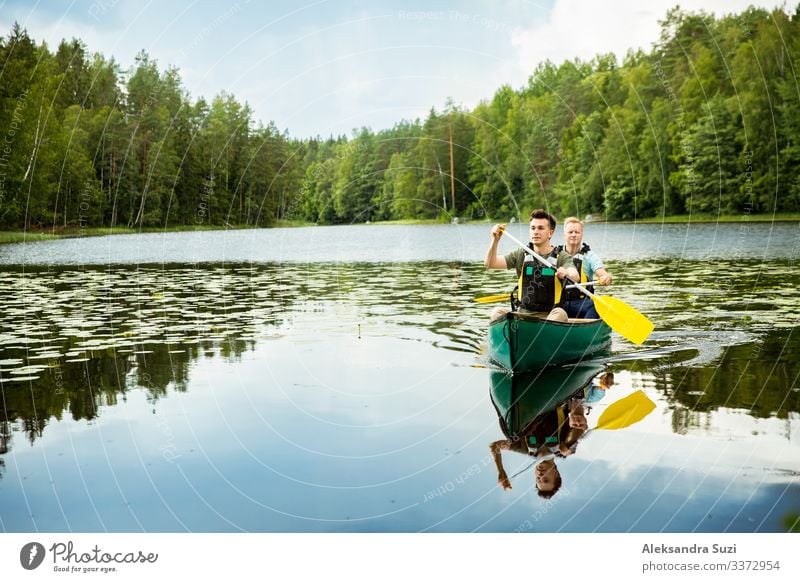 Zwei Männer in Rettungswesten beim Kanufahren auf einem Waldsee. Aktion Abenteuer offen Ausflugsziel entdecken Finnland Glück See Landschaft Lifestyle Mann