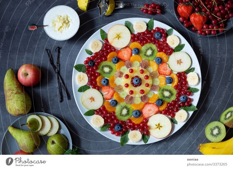 Leckerer gemischter Obstsalat als Mandala auf weißem Teller angeordnet, mit leckerer Creme und vielen gesunden Zutaten Lebensmittel Frucht Apfel Vanilleschote