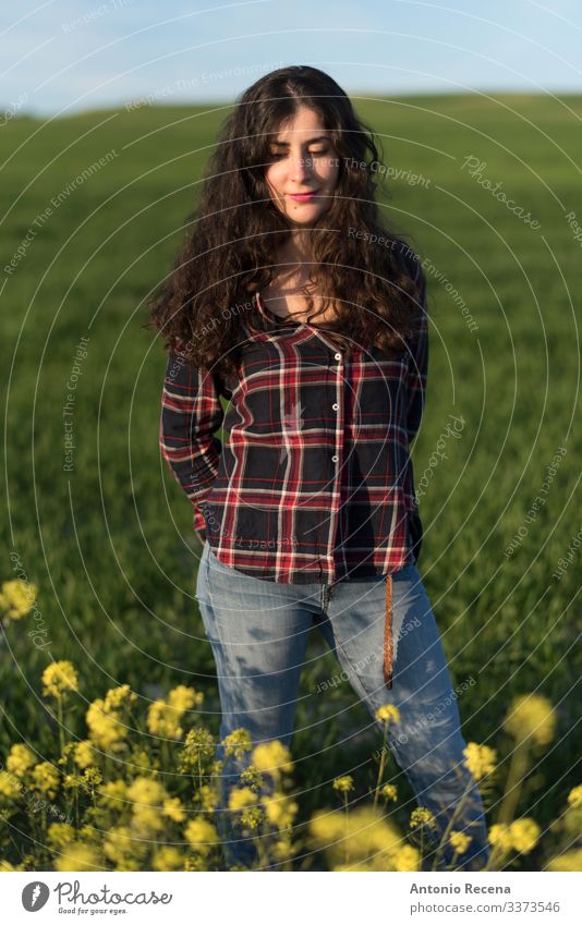 Hübsche Frau im Frühlingsporträt Lifestyle Mensch Erwachsene Blume Wiese Hemd Jeanshose langhaarig stehen Spanisch Sonnenuntergang kariertes Hemd Menschen