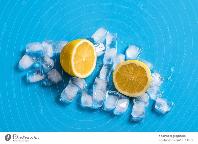 Frische Zitrone, in zwei Hälften geschnitten, auf Eiswürfeln. Zitrusfrüchte Frucht Erfrischungsgetränk Gesunde Ernährung Blauer Hintergrund farbenfroh