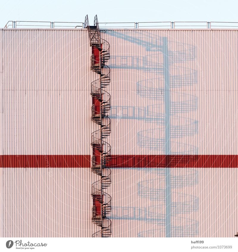 Wendeltreppe im Sonnenaufgang mit langen Schatten Architektur Lager Treppe Fassade Industrieanlage Symmetrie Außenaufnahme rot modern ästhetisch Morgen