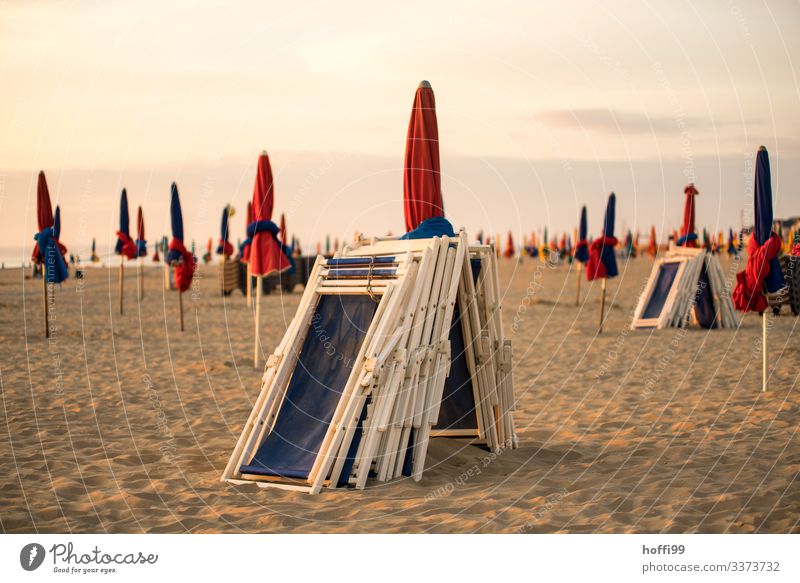 eingepackte Sonnenschirme und Strandliegen bei Sonnenuntergang am Strand von Deauville Umwelt Sand Himmel Wolken Sonnenaufgang Schönes Wetter Küste Meer