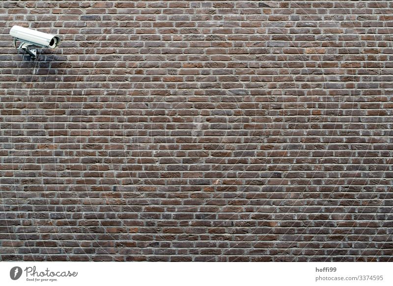 Überwachungskamera an Aussenmauer Gebäude Mauer Wand Fotokamera Backstein Linie Streifen bedrohlich dunkel Stadt Sicherheit Schutz Wachsamkeit Angst
