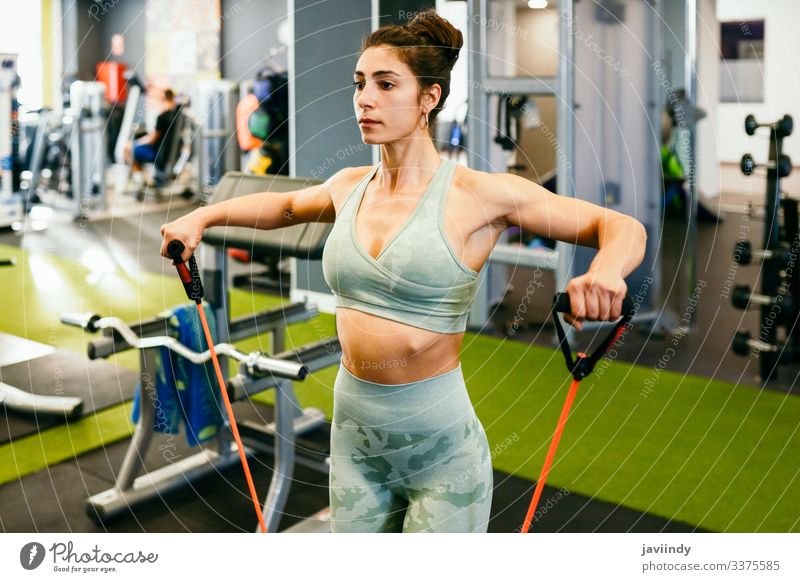 Junge Sportlerin beim Aufwärmen mit Fitnessgummis im Fitnessstudio Frau Training Zahnfleisch elastisch Band Gerät Gesundheit Körper Bizeps Übung Unterleib