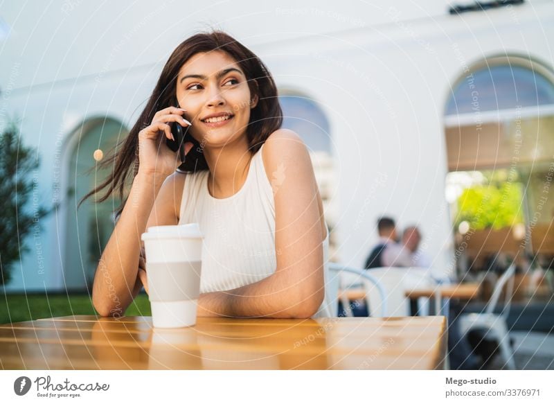 Junge Lateinamerikanerin am Telefon. Glück sprechend Mobile Frau Mädchen im Freien Anruf klug Zelle hübsch jung Kaffeehaus Smartphone Funktelefon Gespräch urban