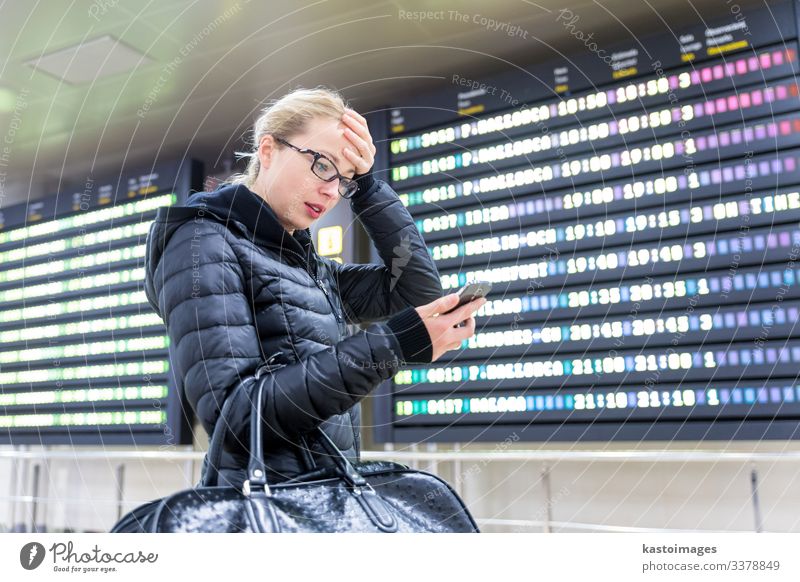Frau am Flughafen überprüft Fluginformationen über Telefon-App. Ferien & Urlaub & Reisen Tourismus Ausflug Winter Dekoration & Verzierung PDA Luftverkehr Mensch