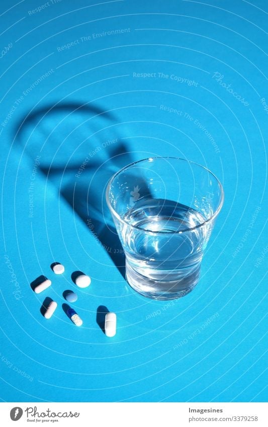 Glas Wasser und Vitamine, Pillen und Tabletten auf blauem Hintergrund mit Text Freiraum Antibiotikum Aspirin Kapsel Nahaufnahme Konzept Kopierraum Heilung