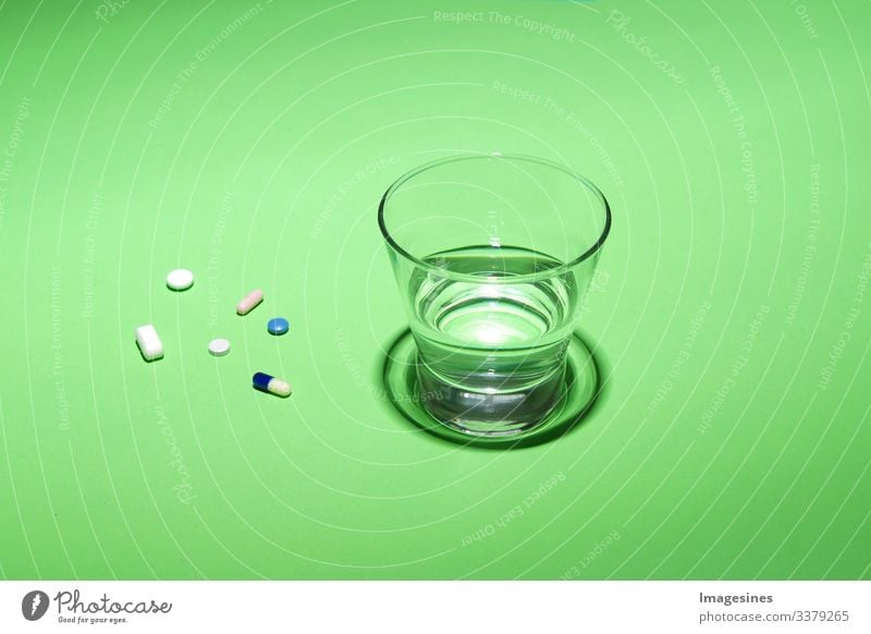 Glas Wasser und Vitamine, Pillen und Tabletten auf grünem Hintergrund mit Text Freiraum grüner Hintergrund Antibiotikum Aspirin Kapsel Nahaufnahme Konzept