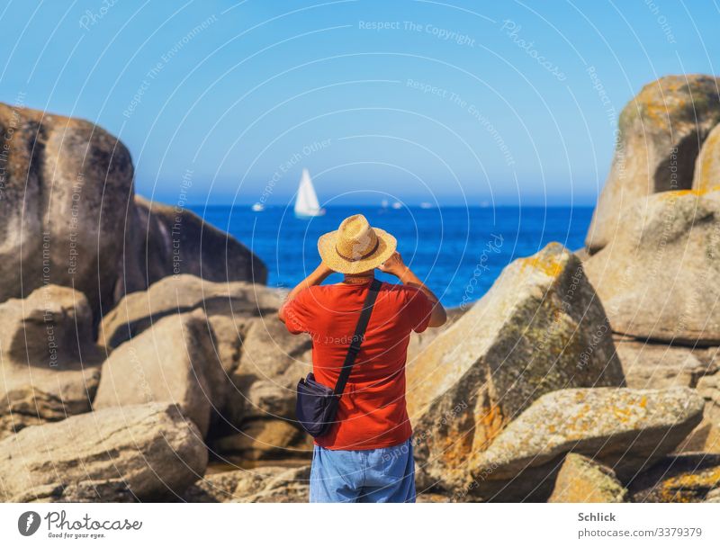 Tourist mit Strohhut in Rückansicht fotografiert in der Bretagne am Meer zwischen Felsen ein Segelschiff Freude Freizeit & Hobby Fotografieren