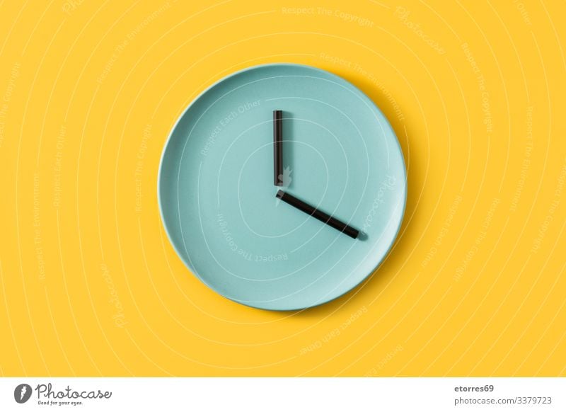 Uhr mit Platte und Strohhalmen auf gelbem Hintergrund Teller gemacht Lebensmittel leer Zeit Konzept Küche Küchengeräte blau schwarz essen Zeit zum Essen Farbe