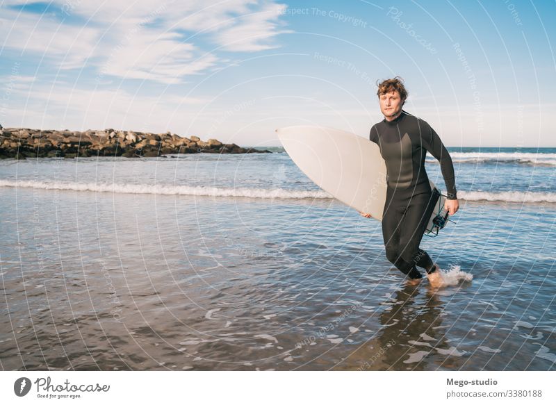Surfer, der mit einem Surfbrett unter dem Arm das Wasser verlässt. Mann Brandung Sport Surfen MEER Meer im Freien sportlich malerisch Küstenlinie Wellen