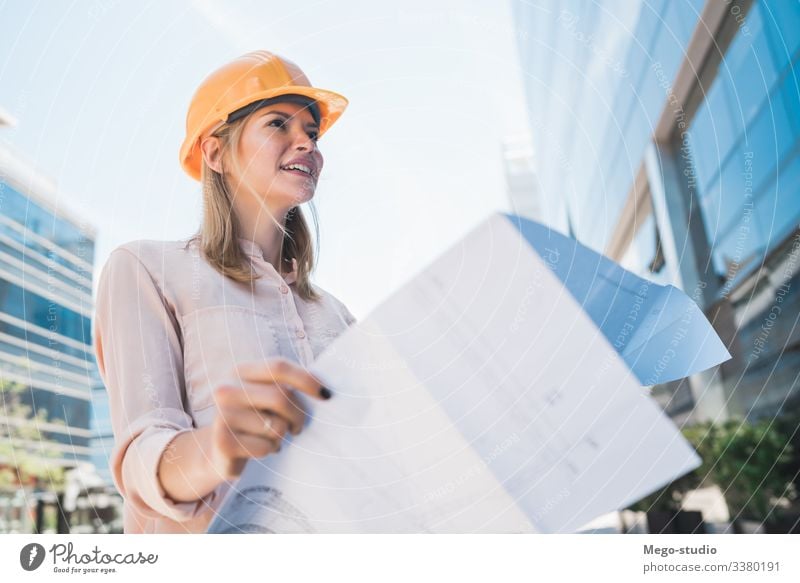 Frau mit Schutzhelm schaut auf Bauplan - ein lizenzfreies Stock