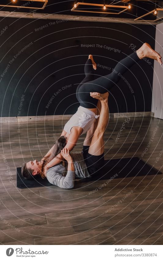 Fröhliches Paar trainiert gemeinsam stehend in gefalteter Blattstellung auf der Matte im Studio Akro-Yoga gefaltete Blattstellung Gleichgewicht Partner heiter