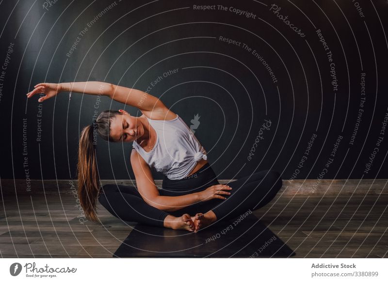 Schlanke barfüßige Frau, die ihren Körper in gebundener Winkelhaltung im zeitgenössischen Studio dehnt Yoga üben Randwinkelstellung Dehnung Übung Training
