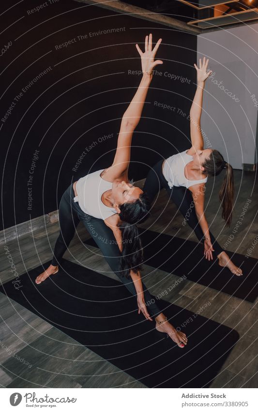 Frauen, die ihren Körper dehnen und Yoga in gedrehter Dreieckshaltung praktizieren drehbare Dreieckshaltung Übung üben Gleichgewicht Dehnung Unterlage Klasse