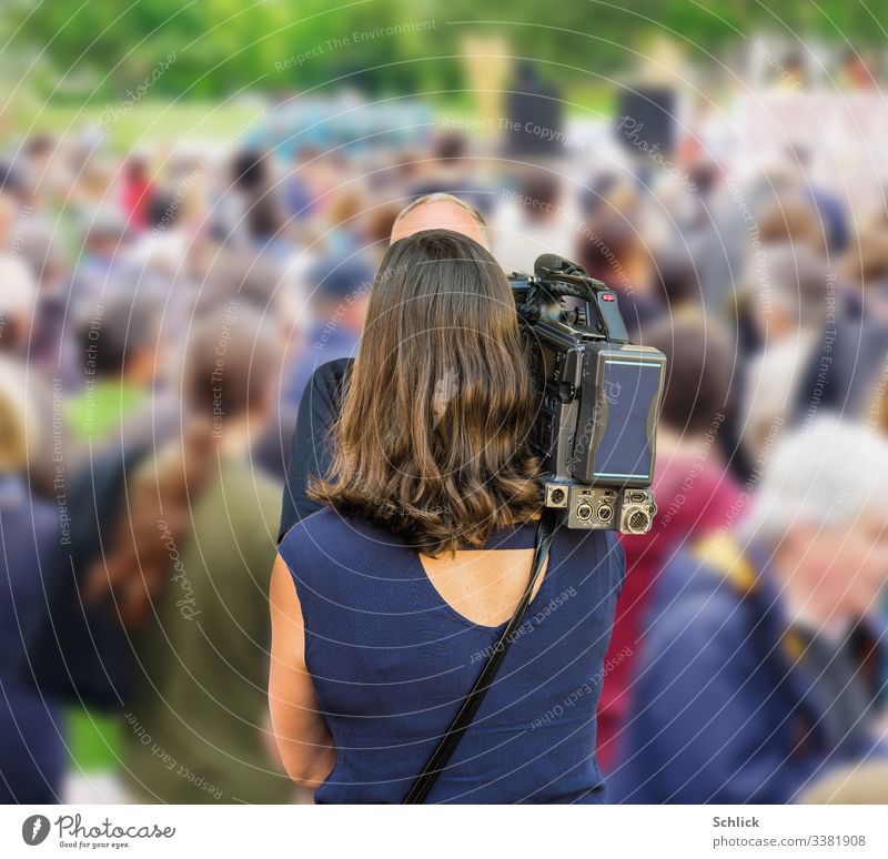 Reporterin mit Kamera filmt Mann mit lichtem Haar vor einer Menschenmenge Rückansicht Rückansicht von hinten filmen Frau Halbnahe langhaarig schwarze Haare